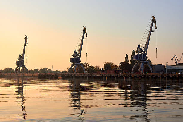 istock Port cranes, harbour cranes on the river bank at sunset 2207834457