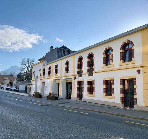 istock A two-story building with arched windows, yellow and red brick facade, and a modern extension on the roof 2207836725