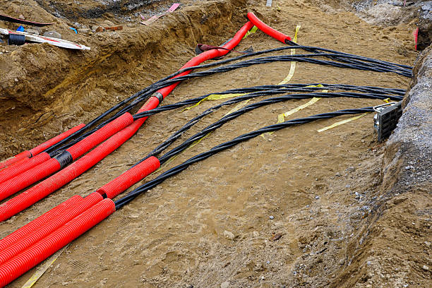 istock Laying new underground high-voltage power cable in red corrugated protective tube 2207838270