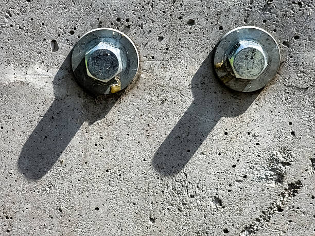 istock Close up of two bolts and washers fastened to concrete surface. 2207838416