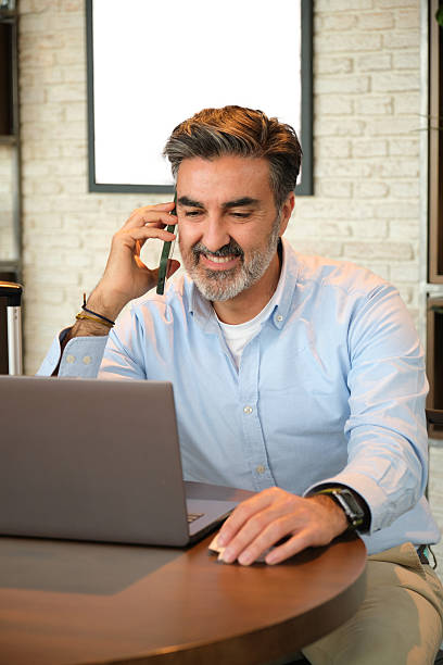 istock Businessman working on laptop and talking on smartphone in cafe 2207838611