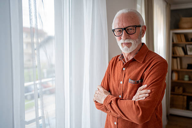 istock Confident senior man smiling by the window at home 2207839072