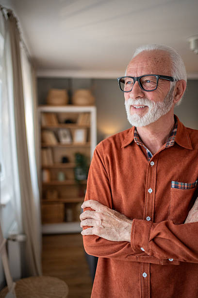 istock Happy senior man smiling and looking away while standing at home 2207839175