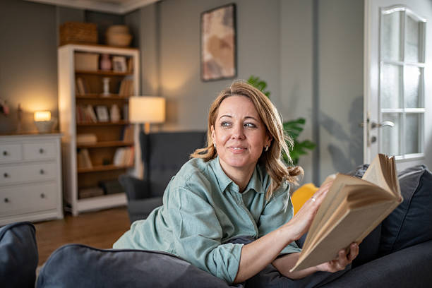 istock Woman lying on sofa reading a book and looking away 2207839465
