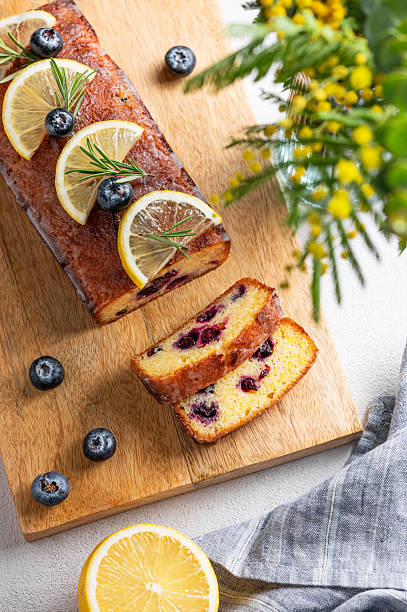 Lemon pie with sugar glaze, blueberries, decorated with rosemary and citrus slices on a wooden board