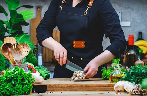 istock Chef cuts oyster mushrooms. Cozy kitchen with wooden table, kitchenware, vegetables, herbs and ingredients for cooking. Healthy vegan food, culinary, recipes, food blogging 2207841531