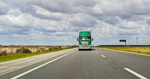 istock Green Truck Driving on Interstate 5 in CA on an Overcast Day 2207842825
