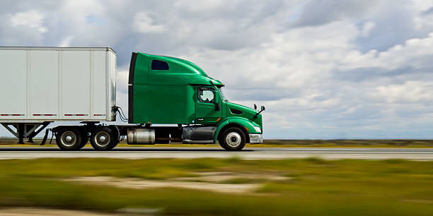 A green truck driving on Interstate 5 in California on an overcast day.