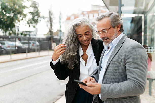 istock Senior couple using smartphone at bus stop in the city 2207843006