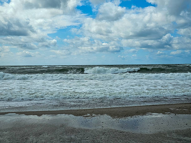 istock Stormy sea waves rolling onto sandy beach under dramatic sky 2207843628