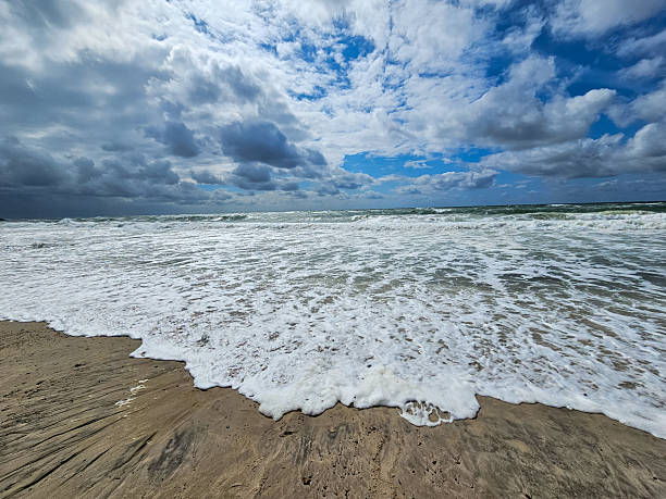 istock Stormy sea waves rolling onto sandy beach under dramatic sky 2207843651