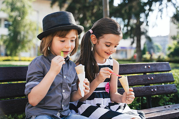 istock Two Kids Savoring Ice Cream on a Bench Outside 2207843838