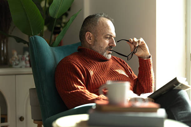 istock Thoughtful mature man reading a book while sitting in a comfortable armchair at home, enjoying a quiet moment 2207844539