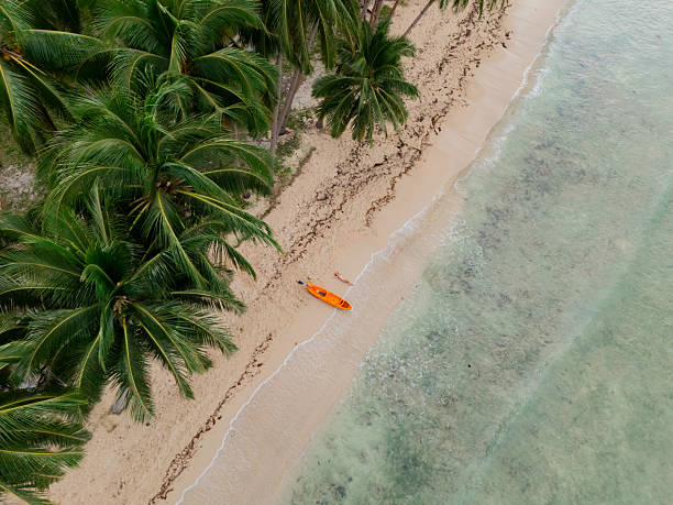 Aerial view of woman relaxing on the idyllic white sand beach where she got kayaking, El Nido, Philippines