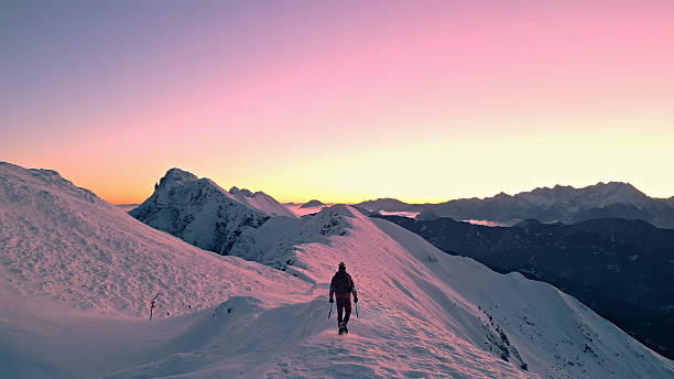 Hiker treks up a snowy mountain slope at sunset, symbolizing perseverance and the beauty of nature's journey.