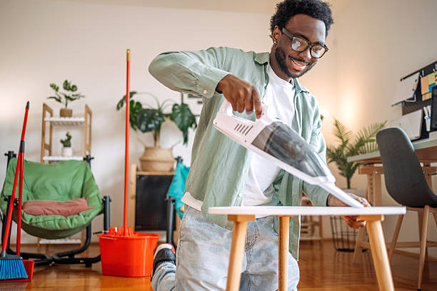 istock Young man cleaning small table in his apartment using vacuum cleaner 2207850159