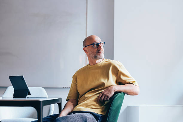 Thoughtful Man Sitting in Office With Tablet During Daytime