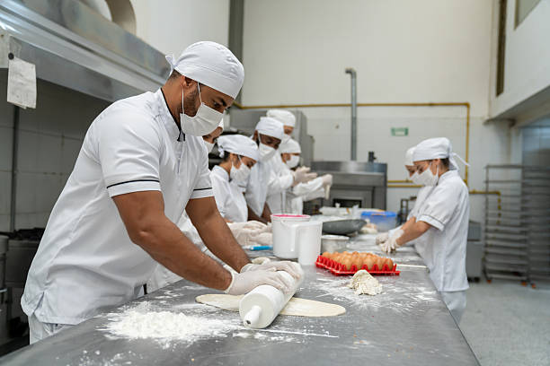 istock Baker kneading the dough using a rolling pin at a food processing plant 2207852430