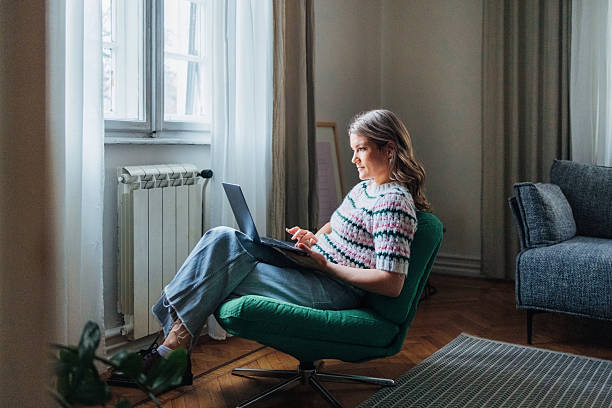 istock Woman Using Laptop While Relaxing in Stylish Living Room Interior 2207852690