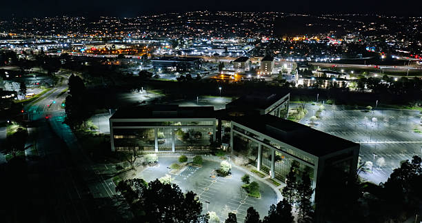 Aerial shot of illuminated nondescript Silicon Valley office buildings surrounded by parking lots at night in Redwood City, California. \n\nAuthorization was obtained from the FAA for this operation in restricted airspace.