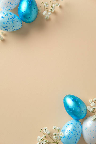 istock Blue and white speckled Easter eggs paired with delicate white flowers on a beige background. 2207855672