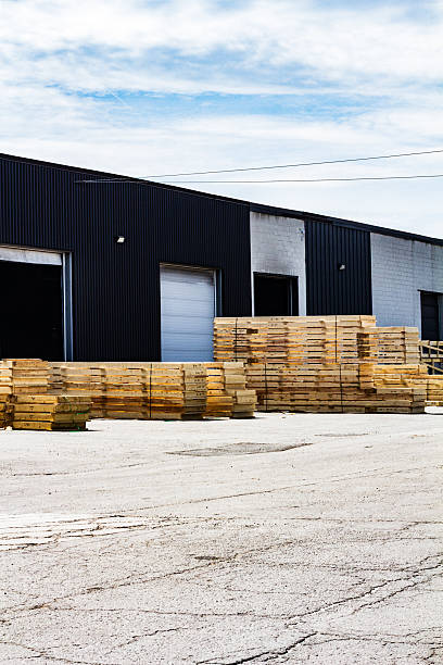 istock Stacked Lumber Outside Industrial Warehouse Under a Clear Sky 2207857470