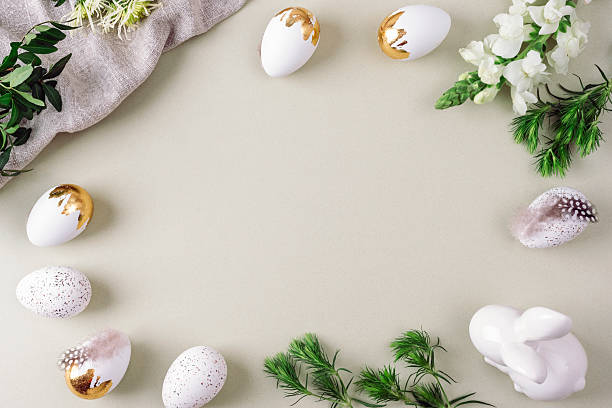 istock White and golden Easter eggs, Easter Bunny, feathers and greenery on soft background. Top view, flat lay, copy space 2207861251