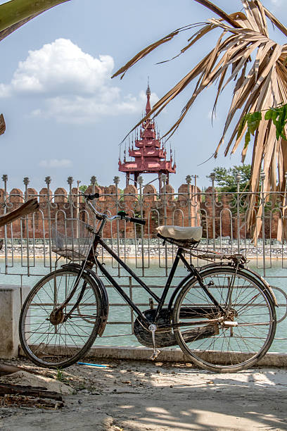An old bicycle is lean on a railing over a water moat before the Royal Palace in Mandalay, Myanmar.