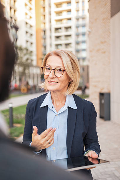 istock Middle-aged businesswoman with tablet in urban setting during daylight 2207865053