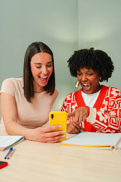 istock Two enthusiastic women joyfully sharing a moment while watching something entertaining on a smartphone device, highlighting their friendship and excitement in this engaging experience together 2207865800