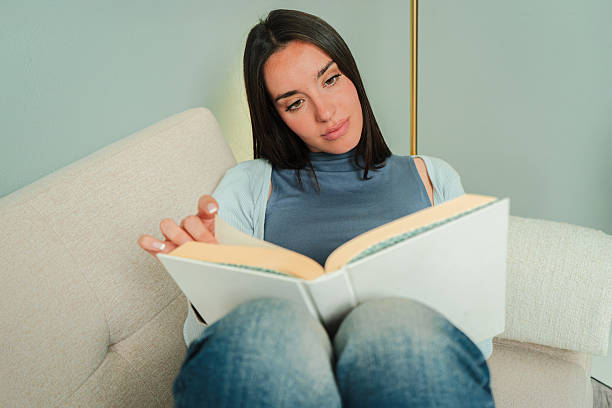 istock A young woman deeply engrossed in reading a captivating book while comfortably relaxing on a plush sofa, enjoying her peaceful moment of solitude and reflection with her favorite literary escape 2207867490