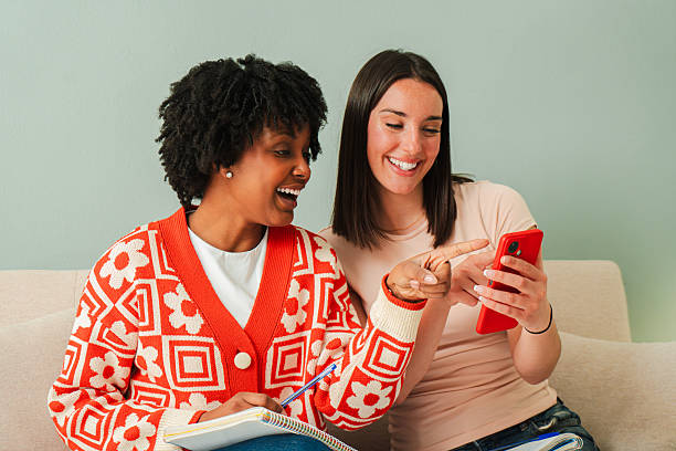 istock Two cheerful women joyfully engaging with a cellphone while sharing a delightful moment of laughter and conversation, showcasing friendship and connection through technology in a lively atmosphere 2207869265