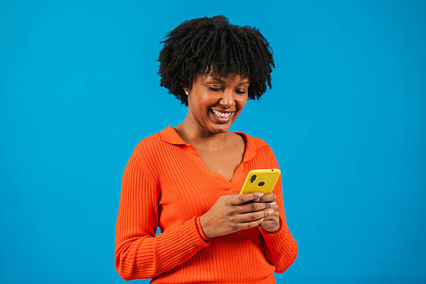 istock Enthusiastic woman joyfully using her smartphone while smiling with excitement, engrossed in content on her mobile phone, showcasing modern communication and connection in a bright, cheerful moment 2207870965