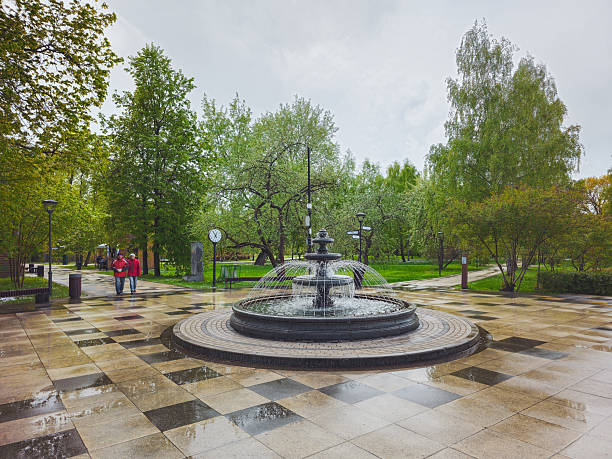 Moscow, Russia - May, 08, 2024: Gloomy spring day, people walking by the fountain Garden of the Future, Botanical Garden Moscow.