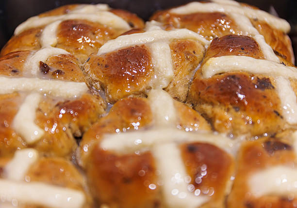 Looking down from above onto a seasonal food background of sticky and sweet Easter hot cross buns with copy space