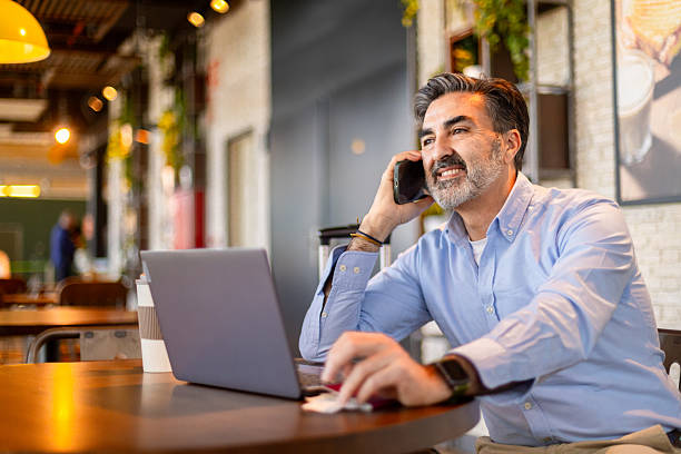 istock Businessman working remotely in cafe and talking on phone 2207873544