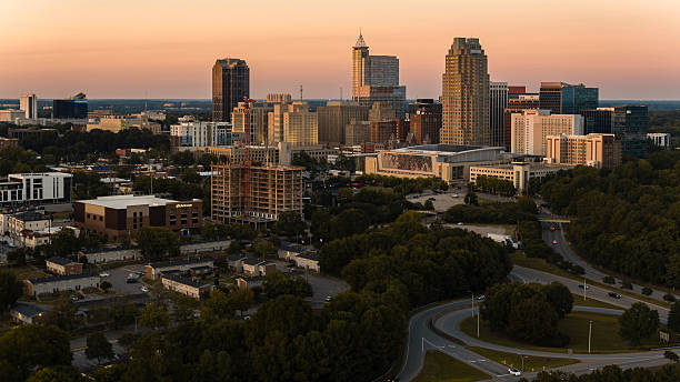 istock Ring road junctions leading to Downtown Raleigh, NC urban skyline. Construction sites and gantry cranes tower the cityscape at sunset 2207874115