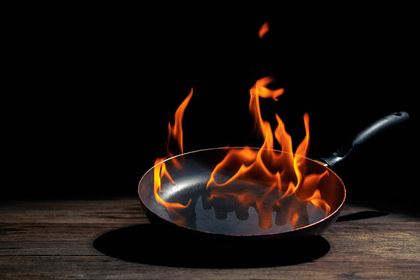 istock Black cooking pan with flames placed in kitchen on dark background table. 2207877676