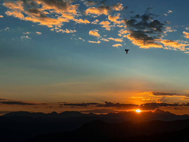 Serene Mountain Landscape at Sunset, Featuring Dark Ridges and a Vibrant Sky Painted with Warm Colors