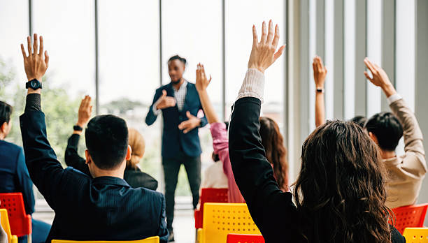 istock During a corporate event businesspeople in a conference and convention engage in discussions. Raised hands demonstrate active participation in a meeting training seminar and teamwork. 2207885824
