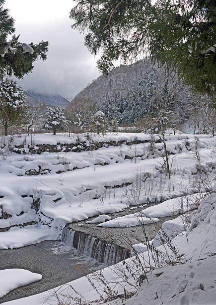 Japanese Satoyama winter snowy scenery with river and mountains in Okuhida, Fukuji onsen, Gifu prefecture in Japan