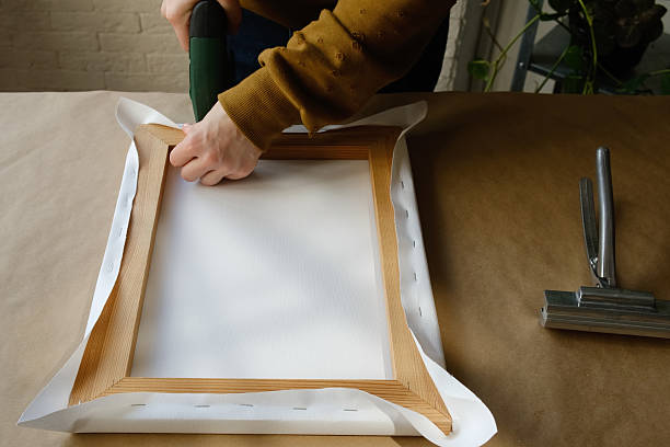 istock Framer stretching canvas on wooden stretcher. 2207891190