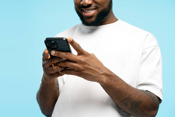 istock Smiling African American man using smartphone on blue background 2207895023