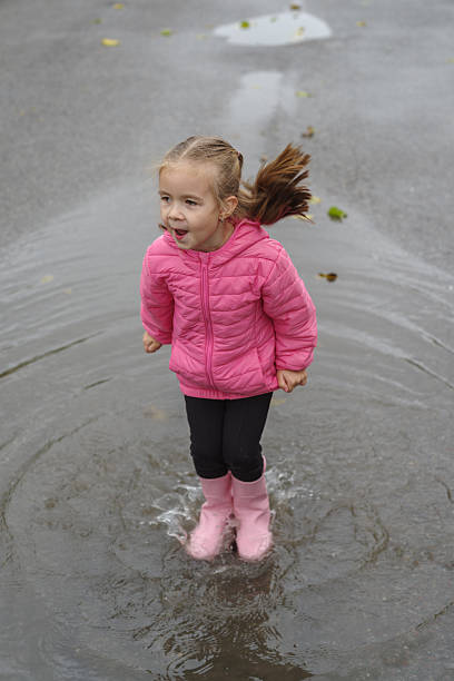 Girl playing in a puddle of water after rain