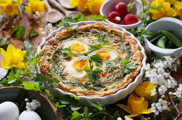 Easter quiche, tart with boiled eggs, vegetables and herbs in a casserole dish, close up view.  Easter food concept