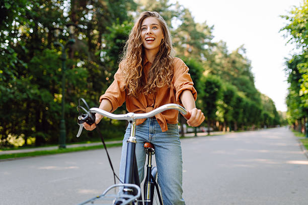 istock Young beautiful woman riding a bicycle in a sunny park. 2207901277