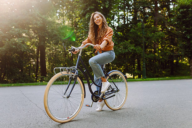 istock Young beautiful woman riding a bicycle in a sunny park. 2207901292