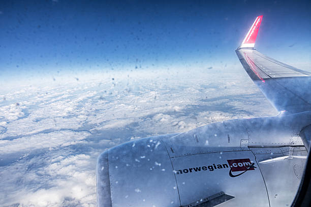 France, Europe - February 25th 2025:  Engine and wing of a Boeing 737 - Max 8 from Norwegian seen through a dirty window in midair