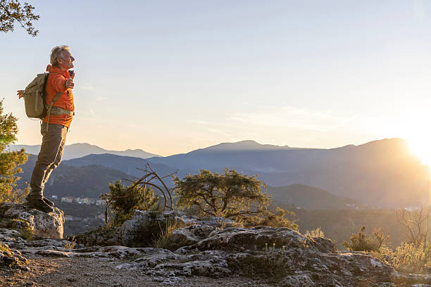 istock Mature hiker stands on mountain top at sunrise 2207908233