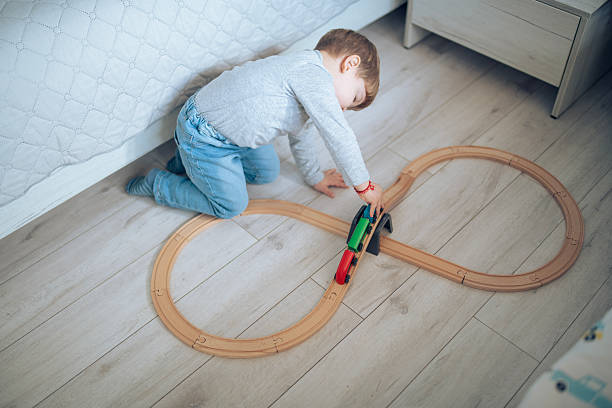 Cute little boy playing with wooden train on the floor at home.